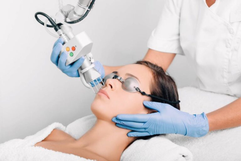 Woman wearing protective glasses, getting laser facial treatment.