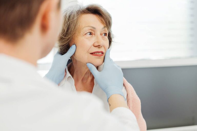 Senior woman, patient talking to dermatologist doctor as he examines her face.